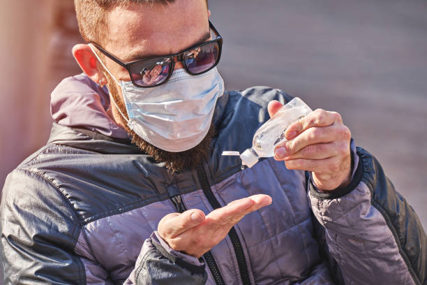istock Man wearing mask uses antibacterial gel on hands 1216431218