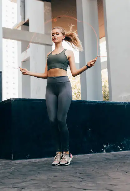 Blonde woman jumping the rope outdoors.