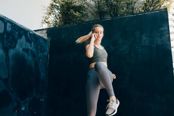 entrenamiento cardiovascular: fit blonde woman doing a dynamic exercise outdoors - jumping women running vitality fotografías e imágenes de stock