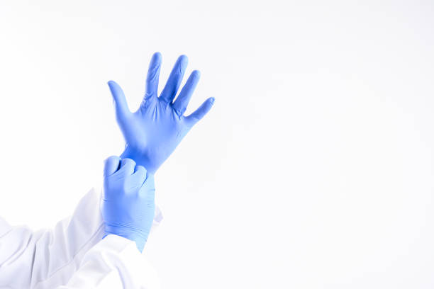 Hands wearing a blue latex glove, isolated on white background Medicine doctor putting on protective gloves before examination isolated on blue background putting on latex gloves stock pictures, royalty-free photos & images