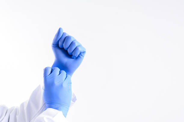 Male doctor's hands putting on blue sterilized surgical gloves Coronavirus concept. COVID-19. Doctors are heroes. Doctor hands in medical gloves showing sign fist of resistance on white background putting on latex gloves stock pictures, royalty-free photos & images