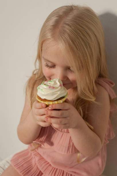 istock Little girl eats sweet cake with cream 1216435375