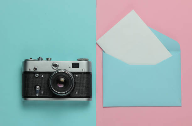 istock Envelope with a letter, retro camera on pink blue pastel background. Top view. Travel concept 1216436689