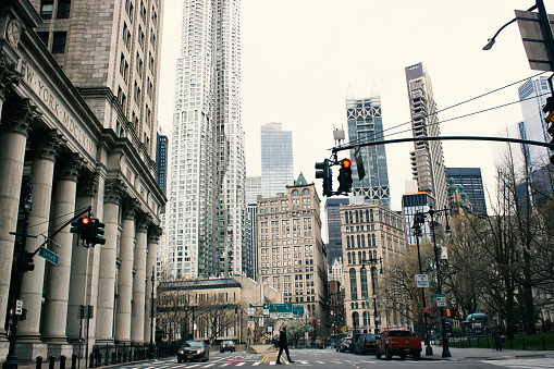 Coronavirus has left the streets of New York City (NYC) empty. Downtown NYC is void of people, here is the financial district (FiDi) in the middle of the workday. There are few cars and people. Building are empty. COVID-19 causes people in New York to social distance and quarantine themselves as everyone works from home.