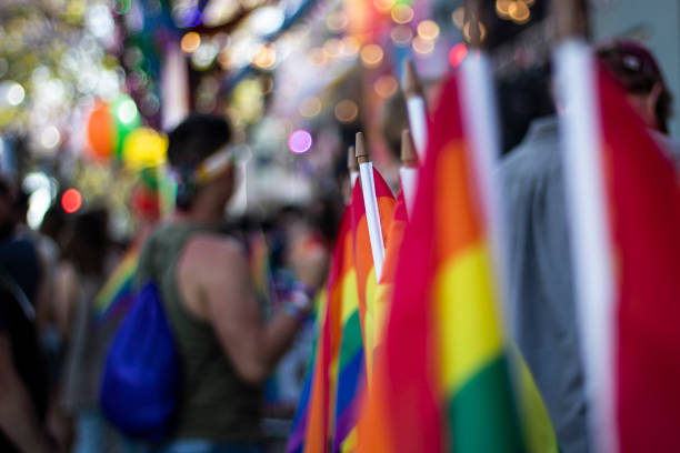 bandera arco iris gay en el desfile de orgullo gay con participantes borrosos en el fondo - gay pride flag fotografías e imágenes de stock