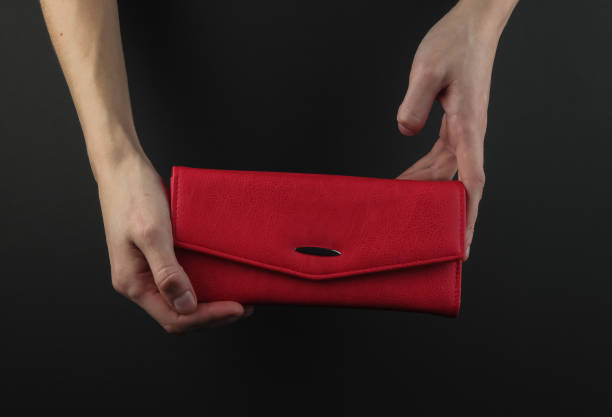 istock Female hands holding red leather purse on a black background 1216438253