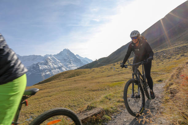 istock Female mountain bikers ride along alpine trail 1216439460