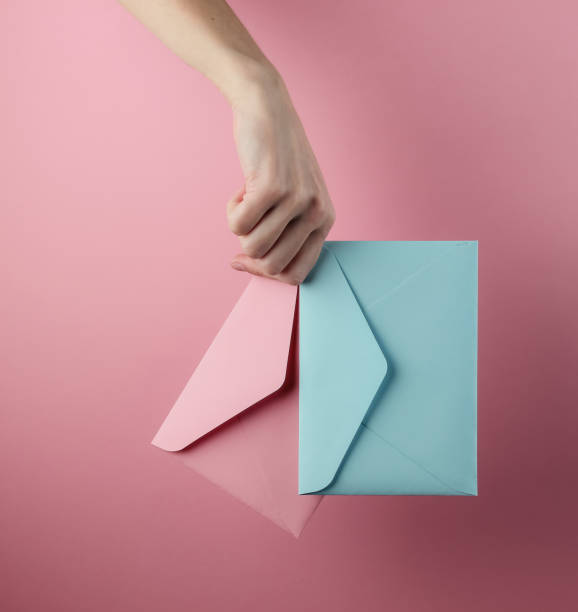 istock Female hand holds two envelopes on a pink pastel background 1216439685