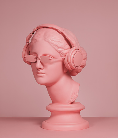 Pink toned plaster head model (mass produced replica of Head of Aphrodite of Knidos) with headphones and sunglasses