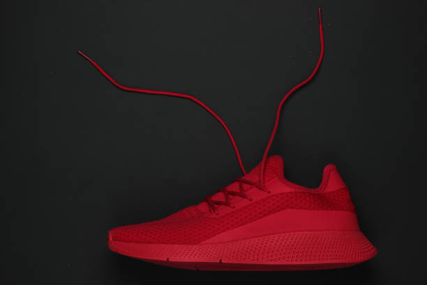 istock Red sports sneaker with an unbound lace on a black background. Top view 1216440465