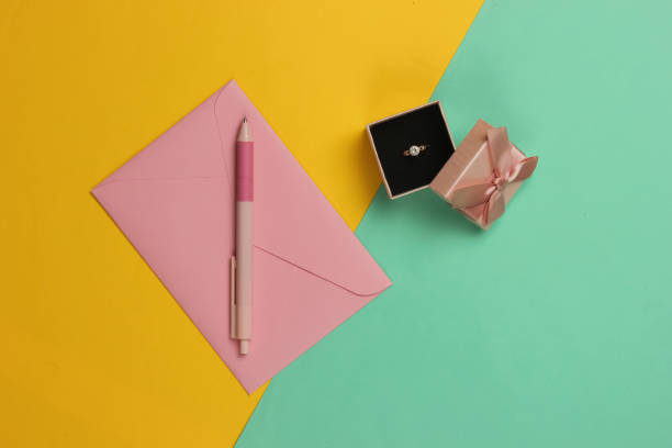 istock Engagement gold ring with diamond in a gift box, envelope with wedding invitations on blue yellow background. Top view. Flat lay 1216440806