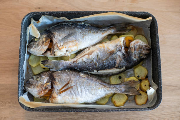 istock Three sea breams in a pan, baked with sliced potatoes. 1216440971