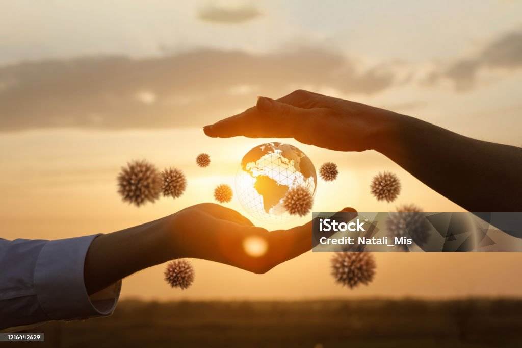 The concept of protecting the world from coronavirus. The concept of protecting the world from coronavirus.Hands protects the globe from viruses against the backdrop of a sunny sunset. Coronavirus Stock Photo
