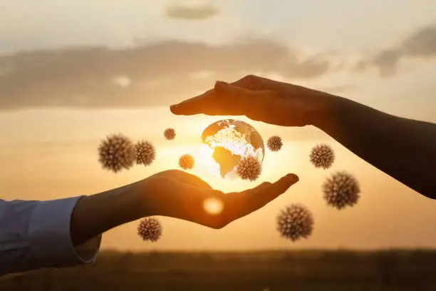 The concept of protecting the world from coronavirus.Hands protects the globe from viruses against the backdrop of a sunny sunset.