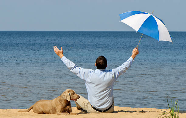 happy man with dog and umbrella on seacoast