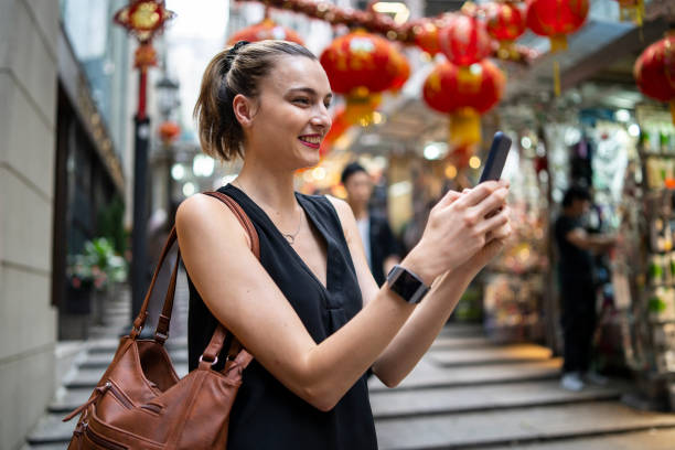 istock Smiling woman browsing on smart phone on street with red lanterns 1216444079