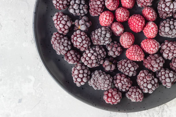 istock Frozen berries (blackberries and raspberries), covered with hoarfrost on a black ceramic plate. Home harvest. 1216444297