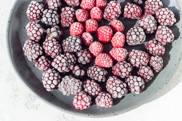 istock Frozen berries (blackberries and raspberries), covered with hoarfrost on a black ceramic plate. Home harvest. 1216444459