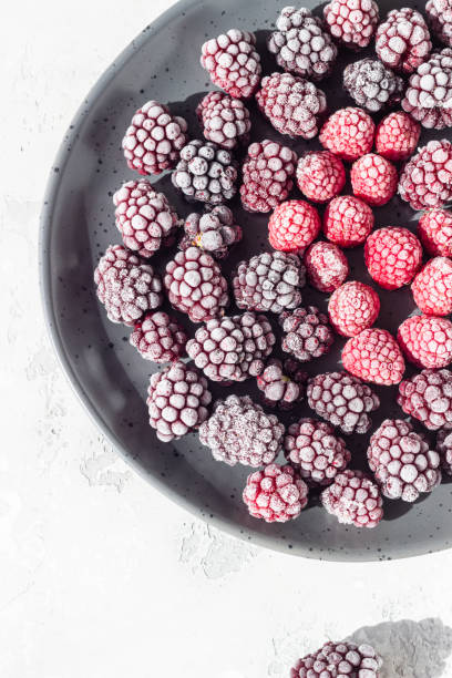 istock Frozen berries (blackberries and raspberries), covered with hoarfrost on a black ceramic plate. Home harvest. 1216444586