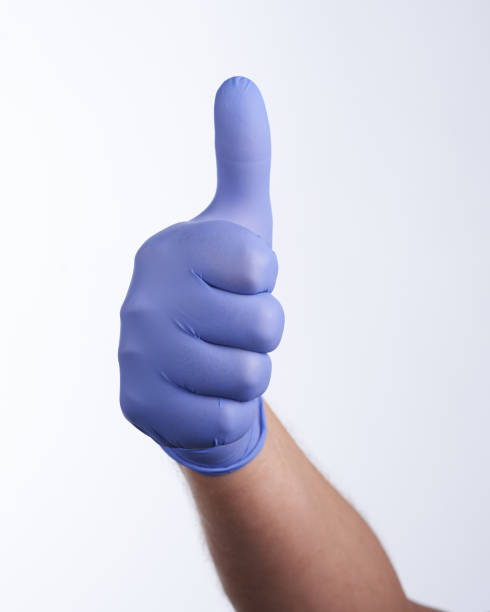 Right hand in blue glove, thumb up stock photo