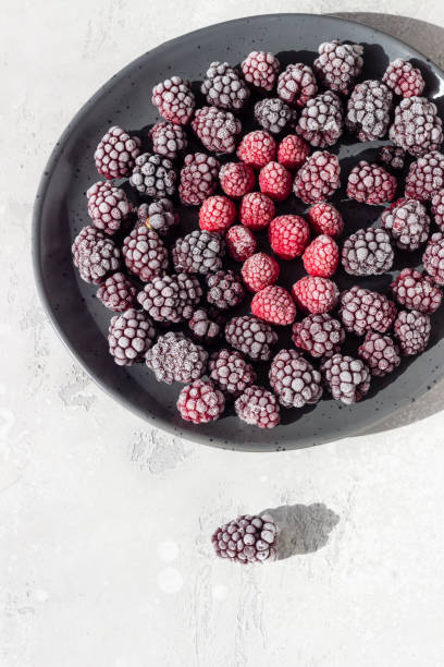 istock Frozen berries (blackberries and raspberries), covered with hoarfrost on a black ceramic plate. Home harvest. 1216445020
