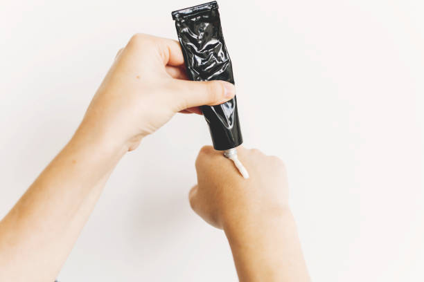 istock Hand applying moisturizing cream from black tube after washing hands and using alcohol gel during virus epidemic. Treatment for dry skin. Luxury skin care. Hand cream. Avoiding dry skin 1216445078