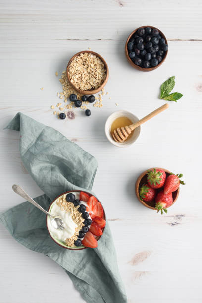 tigela de iogurte com frutas e mingau de aveia na mesa - spoon napkin silverware white - fotografias e filmes do acervo