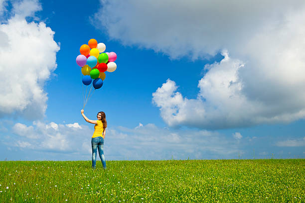 istock Girl with balloons on grass under blue sky with white clouds 121645151