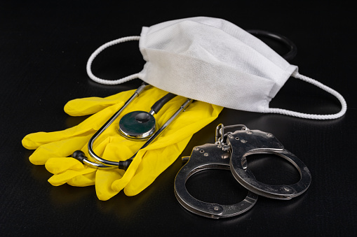Hygienic mask, stethoscope and handcuffs. Accessories for doctors and patients for personal protection. Dark background.