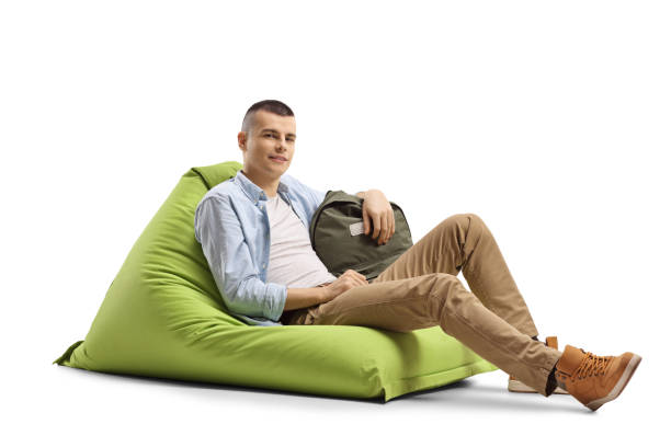 istock Male student sitting on a green bean bag chair 1216453744