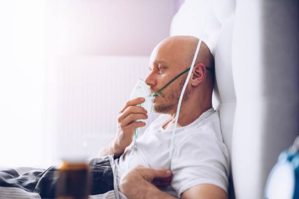 istock Man breathing through oxygen mask in bed. Covid-19 patient. 1216454170