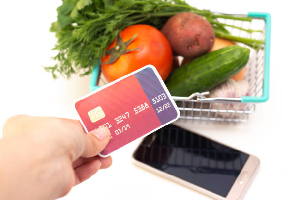 ordering food at home in connection with isolation from the coronavirus. phone and card. a person places an order. tomato, cucumber, greens in a basket. ordering food at home in connection with isolation from the coronavirus. phone and card. a person places an order. tomato, cucumber, greens in a basket. 2933 stock pictures, royalty-free photos & images