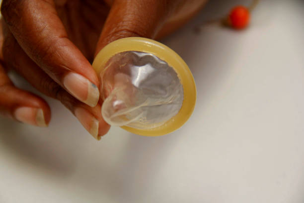 hand holds male condom salvador, bahia / brazil - february 6, 2013: hand holds male condom, contraceptive method and also used to control sexually transmitted diseases."n condom photos stock pictures, royalty-free photos & images