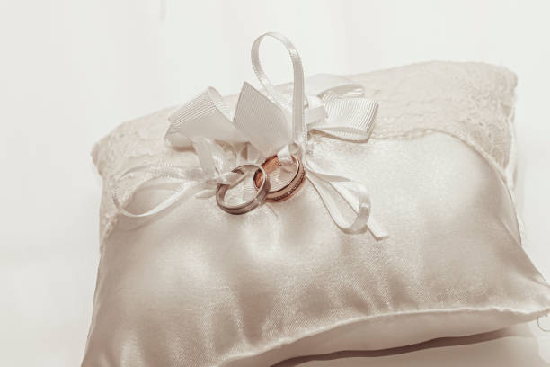 A pair of matching wedding rings tied to a ceremonial pillow.