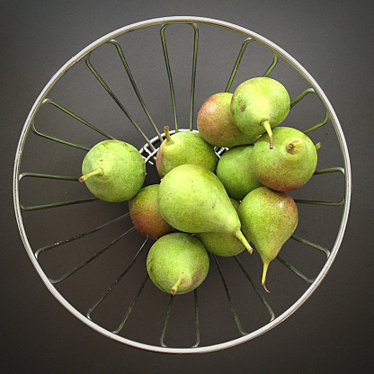 Pears in metal basket on a dark background
