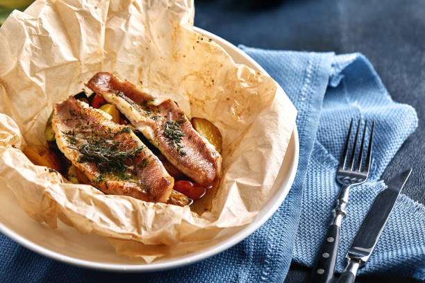 fillet of white fish pollock, cod, sea bass, sea bream with olives, tomatoes and lemon, baked in parchment. traditional italian food fish papillo with bulgur, food photo - sea bass prepared fish food grilled imagens e fotografias de stock