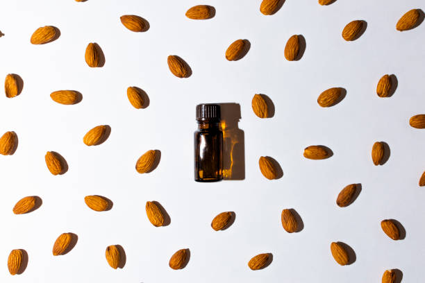 Flat lay brown bottle with aromatic oil on a white background. Mendal is scattered near the bottle. Hard shadows. view from above. Flat lay brown bottle with aromatic oil on a white background. Mendal is scattered near the bottle. Hard shadows. view from above harsh shadows stock pictures, royalty-free photos & images