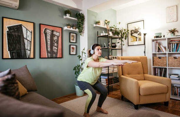 mujer adulta haciendo ejercicio en casa durante la cuarentena - ejercicios agachados y de fuerza - body building exercises audio fotografías e imágenes de stock