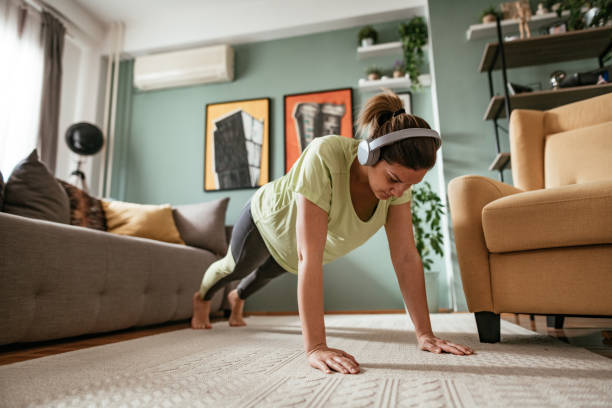 mujer adulta haciendo ejercicio en casa durante la cuarentena, haciendo flexiones - body building exercises audio fotografías e imágenes de stock