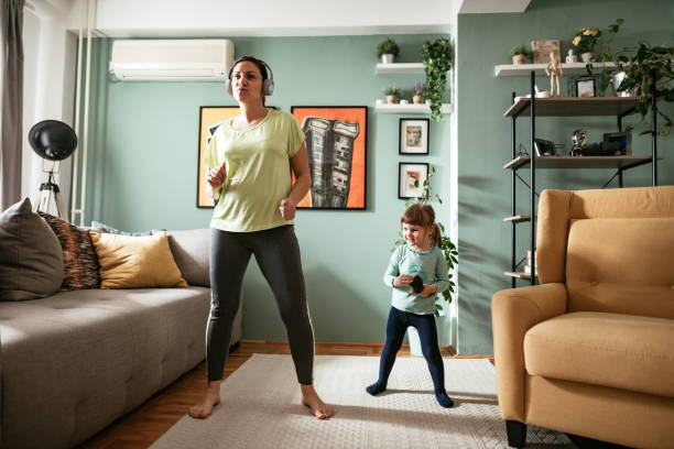 mujer adulta bailando en casa durante la cuarentena con hija de tres años - mothers audio fotografías e imágenes de stock