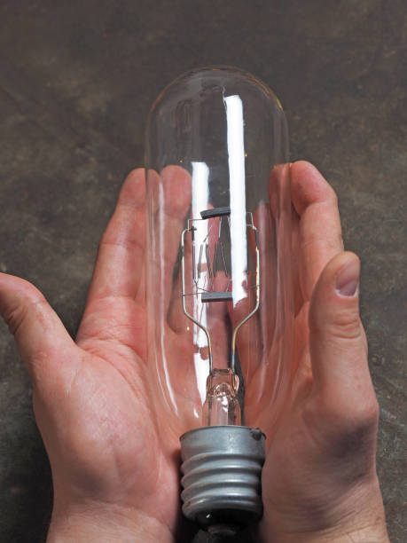 istock a large old incandescent lamp in men's hands on a dark background 1216459553
