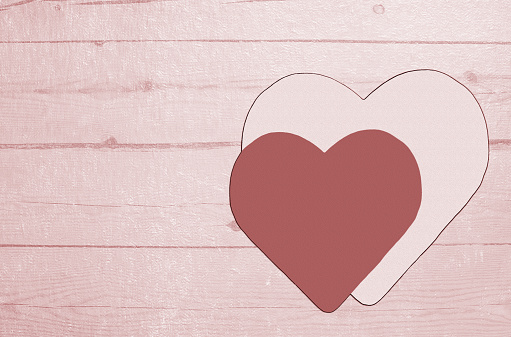 Hearts on a textured wooden background, love concept. Tinted in pink