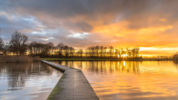 istock Wooden walkway in lake under orange sunset 1216461112
