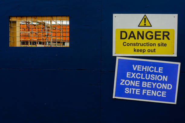 istock Fence around a construction site, with a cutout window allowing people to see through, and warning signs 1216462016