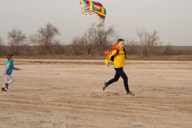 istock Two brothers 10 and 4 years old play on an empty beach. Flying a kite. 1216462096
