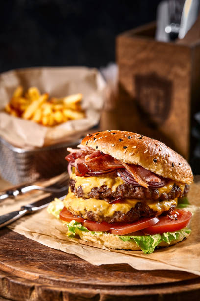 istock Juicy American burger, hamburger or cheeseburger with two beef patties, with sauce and basked on a black background. Concept of American fast food. Copy space 1216463676