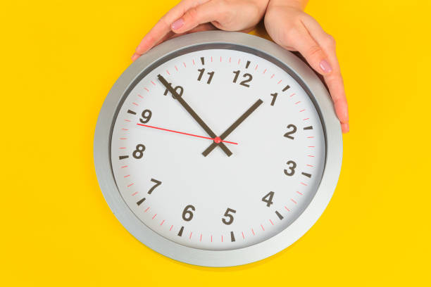 istock Beautiful young woman's hands with clock  on pastel  background - Image 1216464089