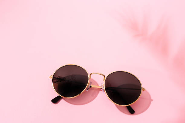 istock round shape black sunglasses on pink background with tropical leaf shadow 1216464148