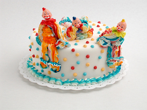 birthday cake decorated with colorful doll of cream clown. White background
