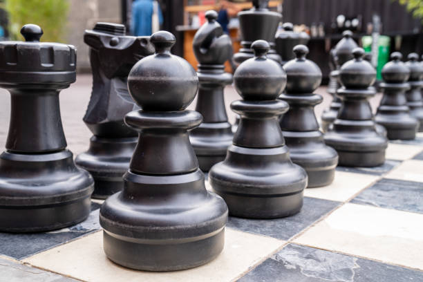 istock Close up of human sized black chess pieces with pawns in front 1216471250
